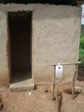 Przykład wykończonej i utrzymanej we właściwym stanie sanitarnym latryny wraz z urządzeniem do mycia rąk tippy-tap